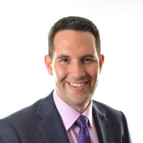 A formal portrait of Ian standing in front of a white background
