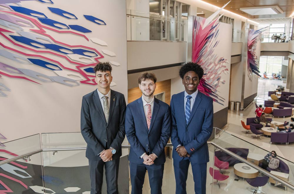 Three professionally dressed undergraduate students posing for the camera