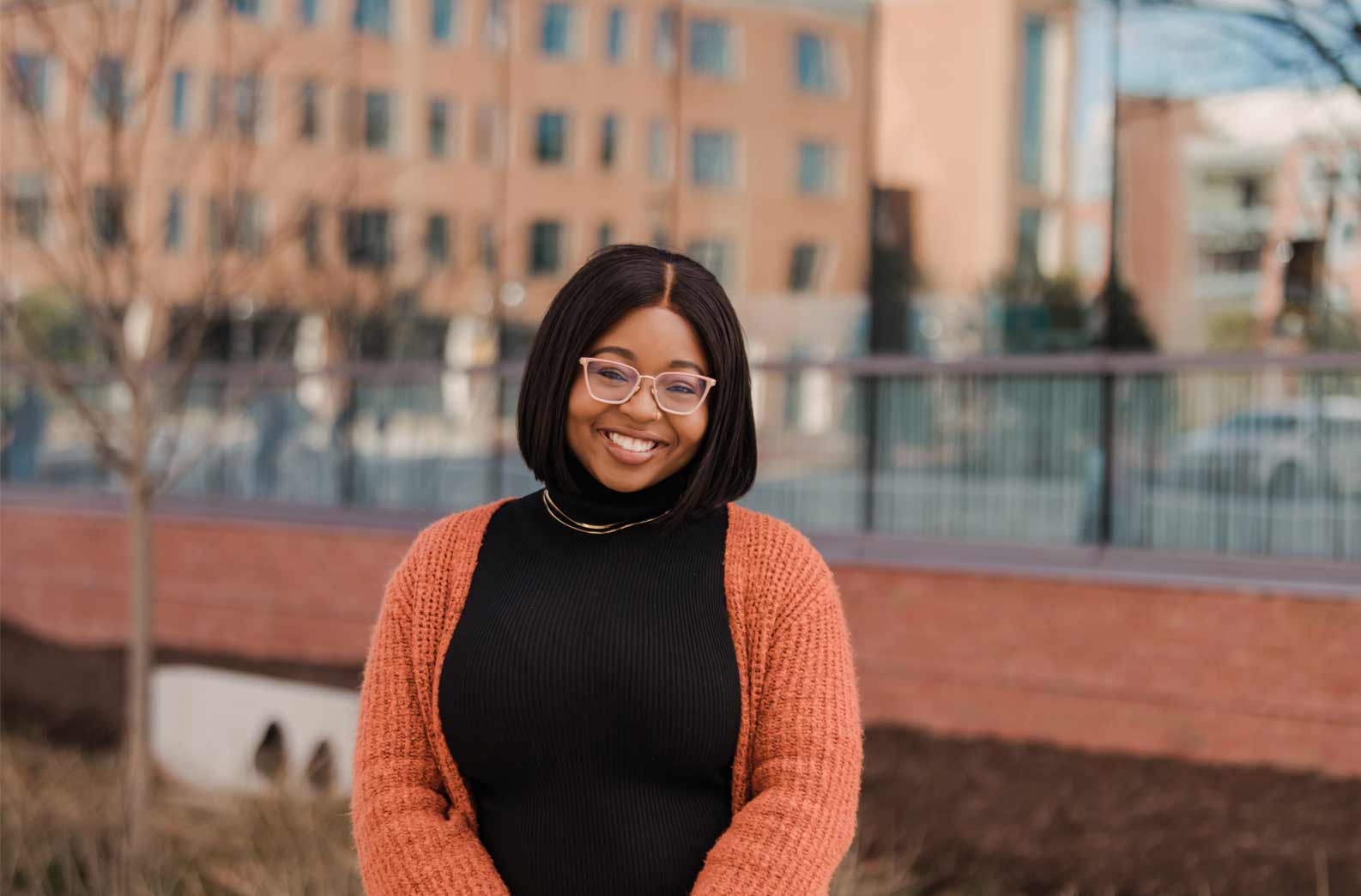 An informal portrait of Adekoya, she is outside on campus, smiling at the camera