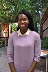 An informal portrait of young researcher, she is smiling as she stsnds outside on academic row