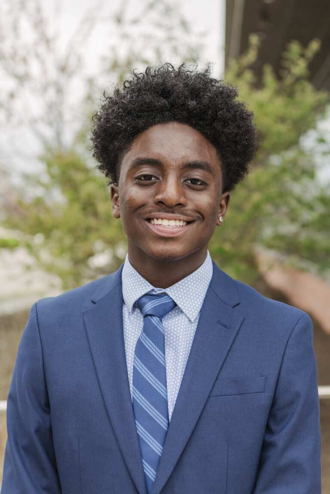 A three quarters portrait of a young undergraduate researcher in a business suit.