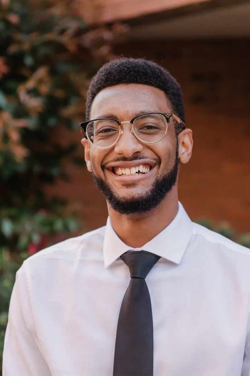 An informal portrait of Joshua, he is smiling at the camera